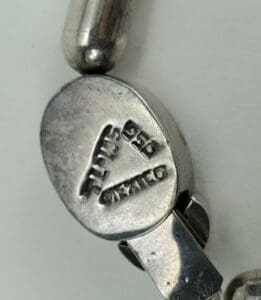 Silver clasp with engraved markings and text.