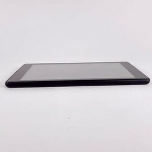 Black tablet lying on white surface.
