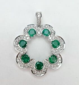 Silver flower pendant with green gemstones.
