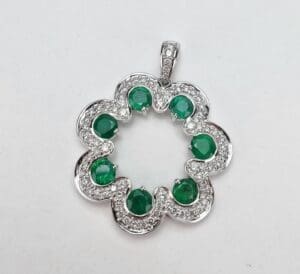 Silver flower pendant with green gemstones.