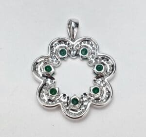 Silver flower pendant with green stones.