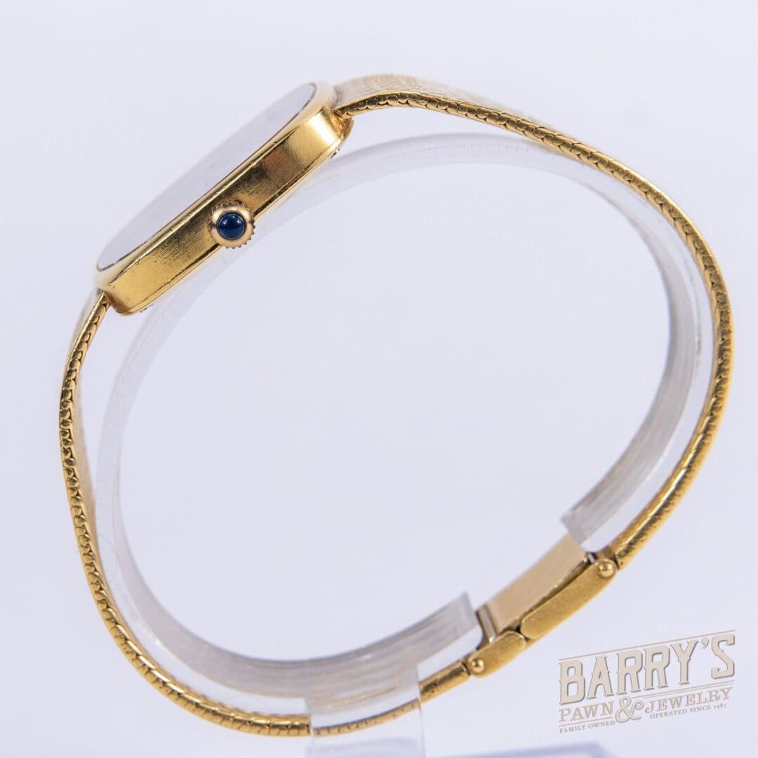 Gold wristwatch with blue gemstone detail.