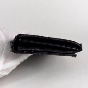 Black wallet held by a gloved hand.