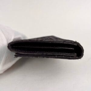 Black wallet held by gloved hand.