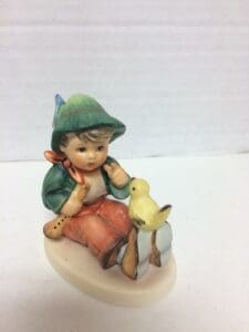 Child figurine with bird on shoulder.