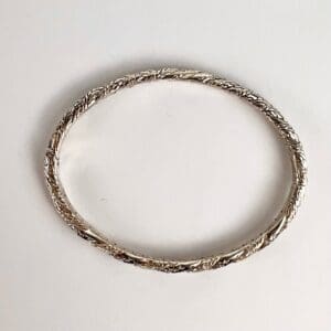 Silver braided bangle on white background.