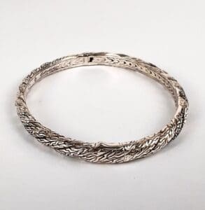 Silver textured bangle on white background.