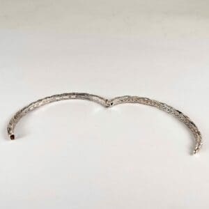 Open silver bracelet on white background.