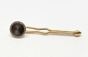Gold tie pin with round black stone.
