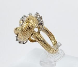 Gold textured ring with diamonds on stand.