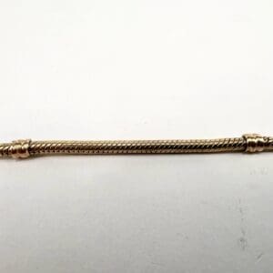 Gold twisted metal rod on white background.