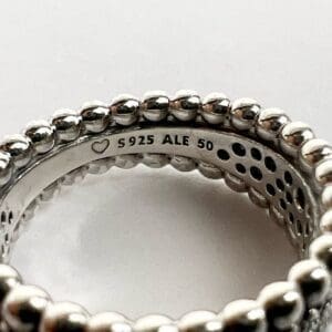 Silver beaded ring with engraved markings.