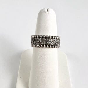 Silver diamond ring on display stand.