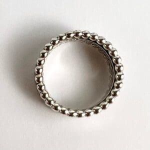Silver beaded ring on white background.