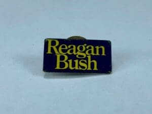 Political campaign pin with "Reagan Bush" text.
