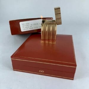 Gold lighter on red box, flame lit.