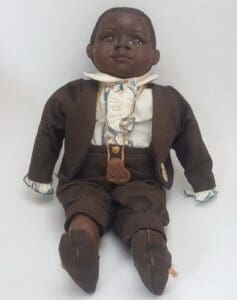 Doll wearing brown suit and white shirt.