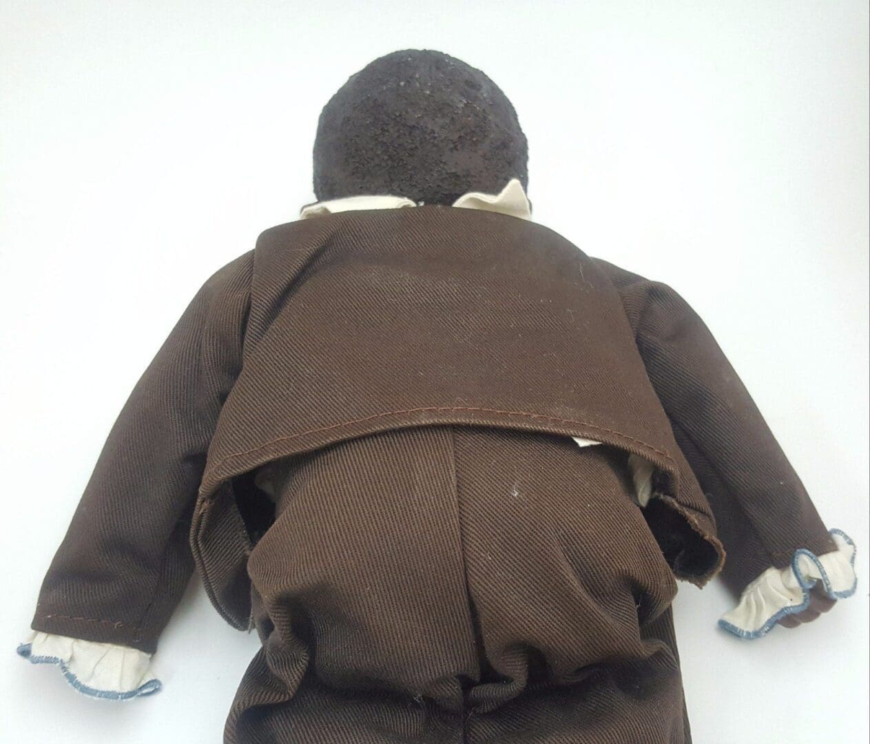 Back of a doll in brown clothes.