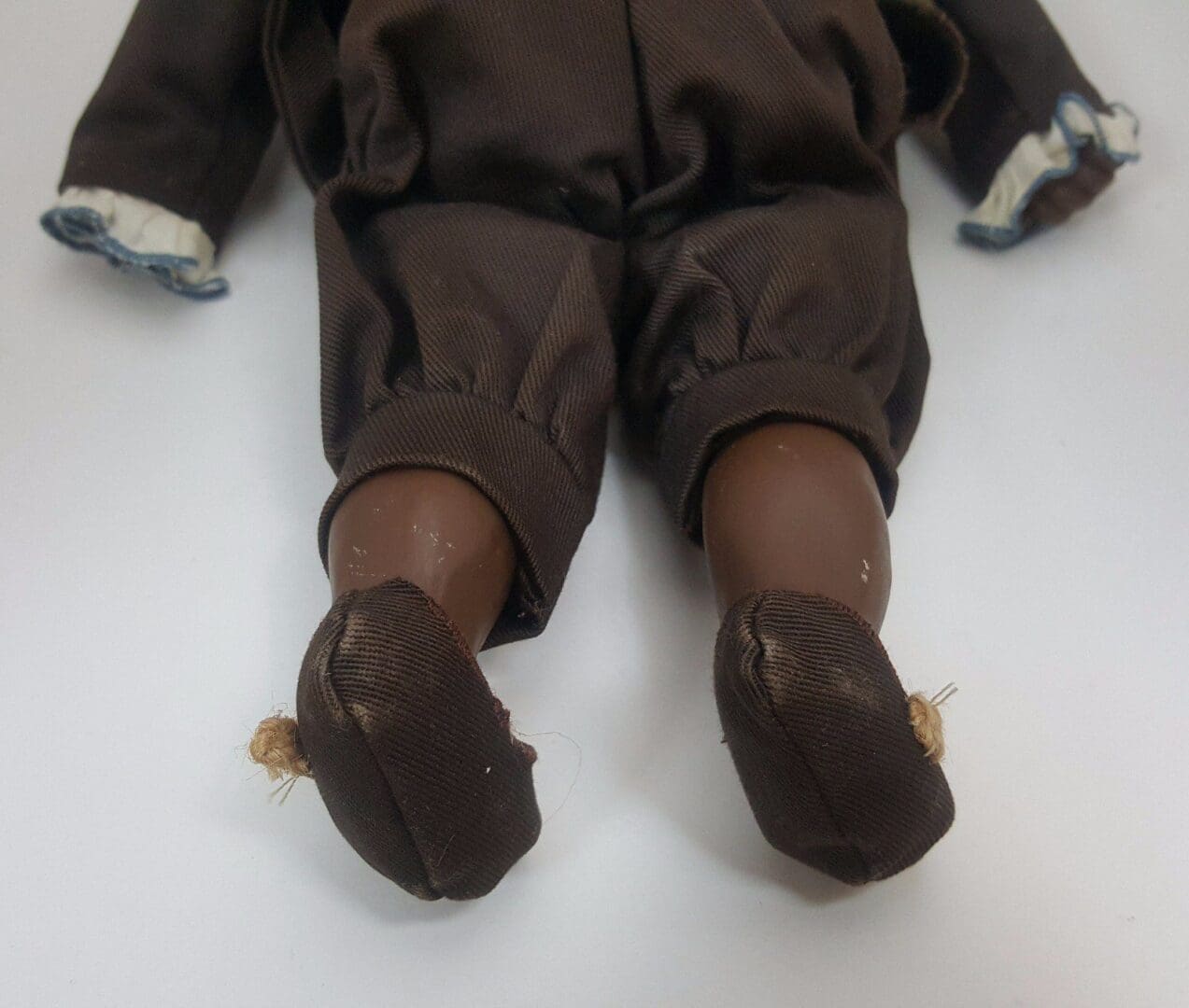 Doll legs in brown pants and shoes.