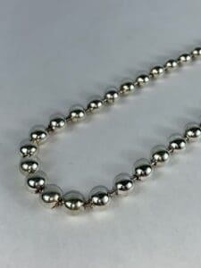 Silver beaded necklace on white background.