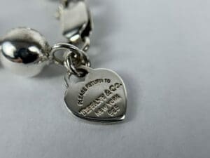 Heart-shaped silver charm with engraved text.