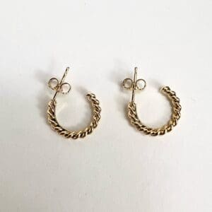 Gold twisted hoop earrings on white background.