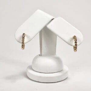 Gold chain earrings on white display stand.