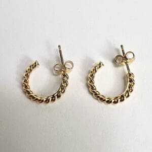Gold twisted hoop earrings on white background.