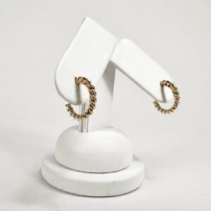Gold hoop earrings on white display stand.