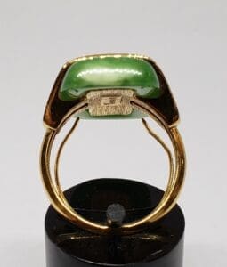 Gold ring with green gemstone on display.