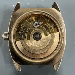 Gold watch movement with visible gears.