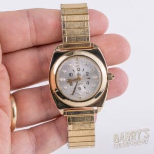 Hand holding a vintage gold wristwatch.