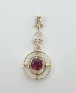 Gold pendant with a red gemstone.