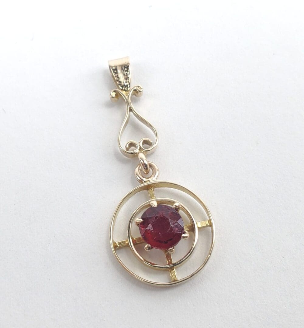 Gold pendant with a red gemstone centerpiece.