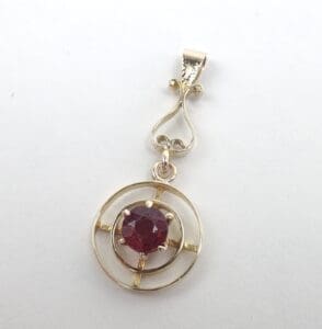 Gold pendant with red gemstone center.
