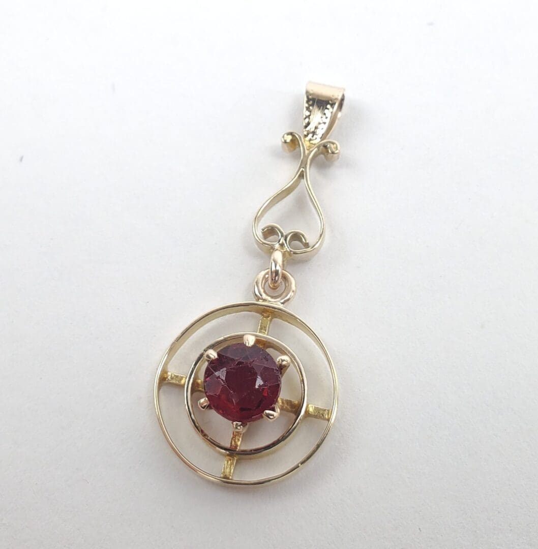 Gold pendant with red gemstone center.