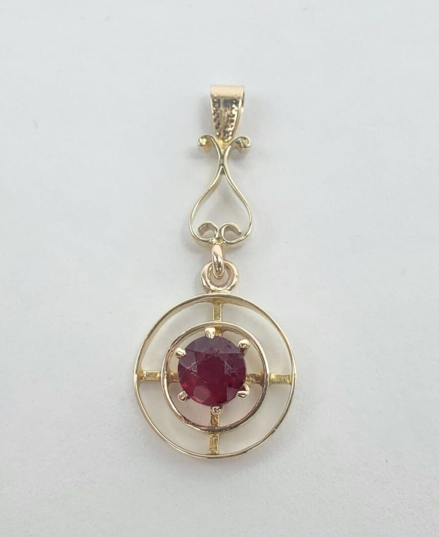Gold pendant with a red gemstone.