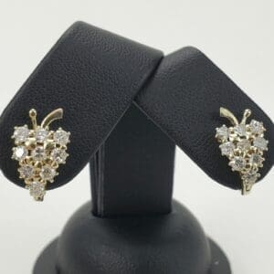 Gold grape cluster earrings on black stand.