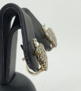 Gold earrings with diamonds on display stand.