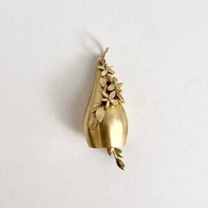 Gold pendant with floral design and leaves.