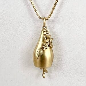 Gold pendant with floral design on chain.