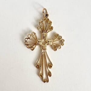 Ornate gold cross pendant with intricate design.