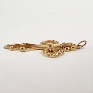 Ornate gold key pendant on white background.