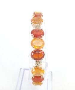 Orange gemstone bracelet on a clear stand.