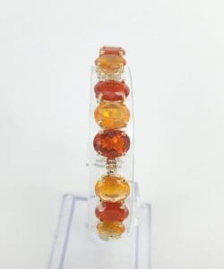 Orange gemstone bracelet on clear display stand.