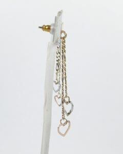 Heart-shaped dangling earrings on display stand.