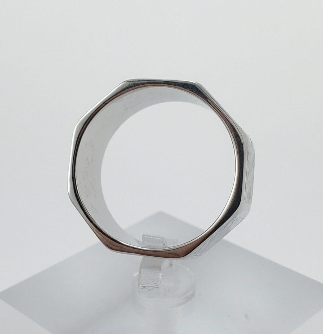 Octagonal silver ring on clear stand.