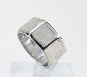 Silver geometric-patterned ring on display stand.