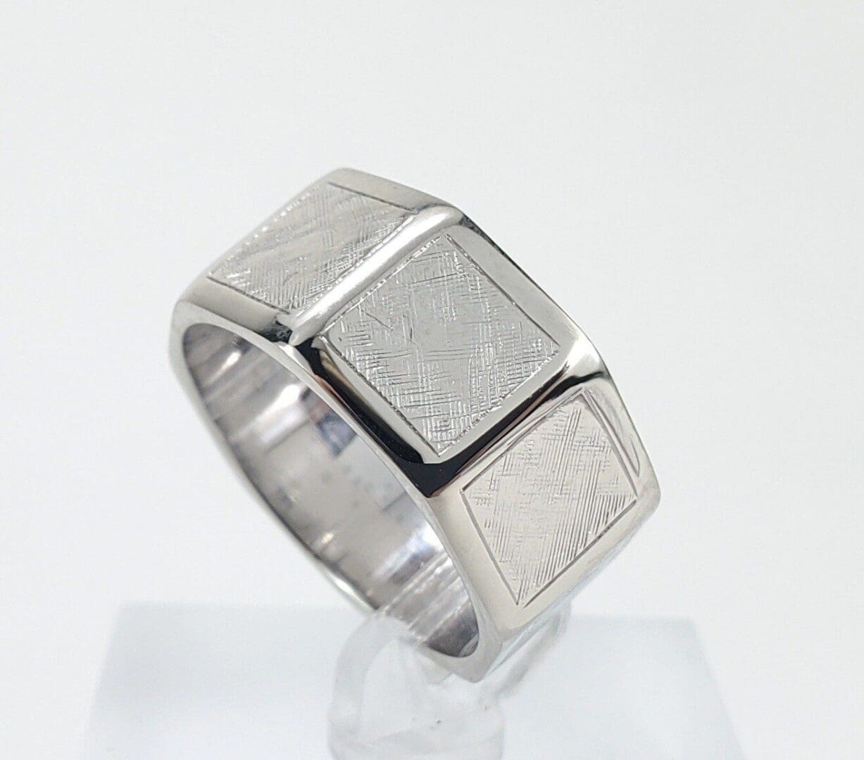 Silver geometric-patterned ring on display stand.