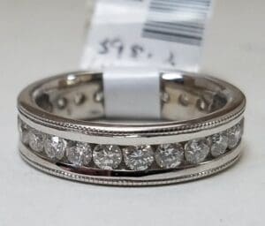 Silver ring with embedded diamonds and tag.
